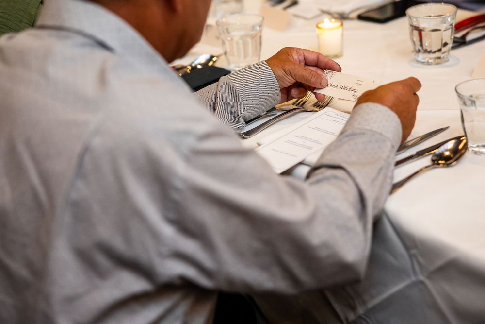 Man in gray shirt reviewing menu at elegant dinner table setting with candles and glassware.