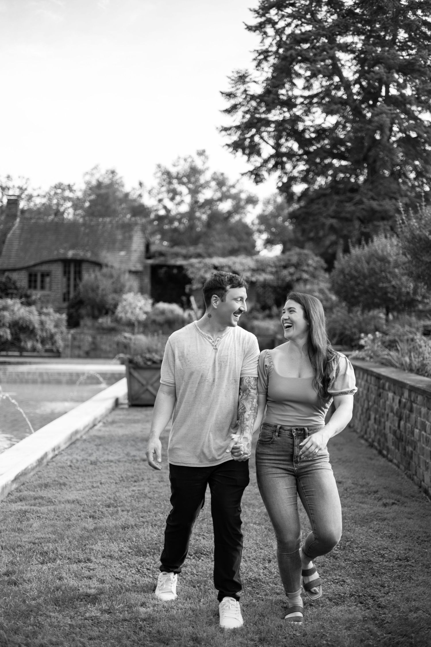 A couple embraces lovingly on a dirt path beside tall ornamental grasses on an overcast afternoon.