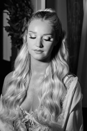 Black and white portrait of a blonde bride with long wavy hair and glamorous makeup wearing lace lingerie.