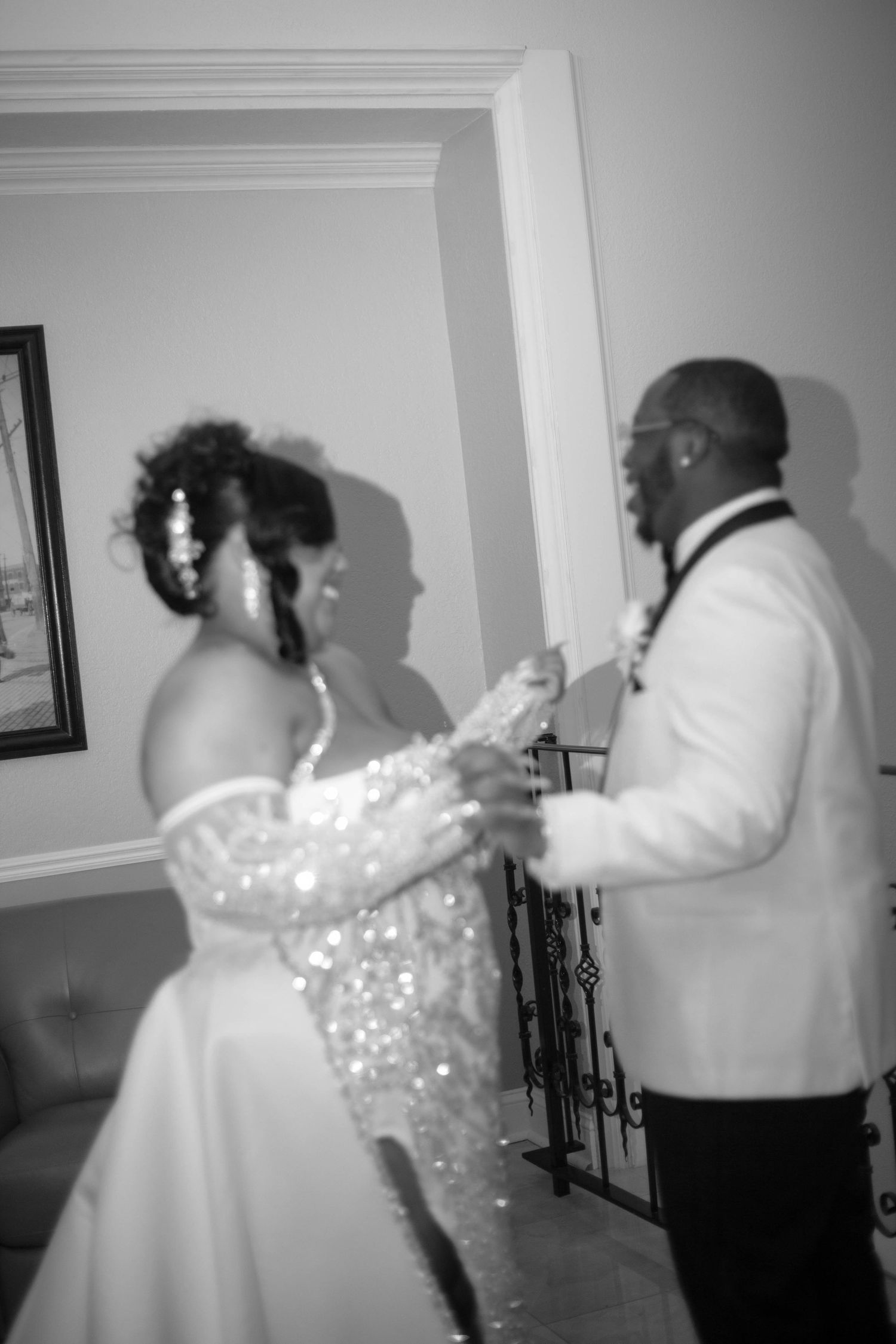 Black and white photo of a bride in a sparkling beaded gown dancing with a groom in a white tuxedo jacket and bow tie.