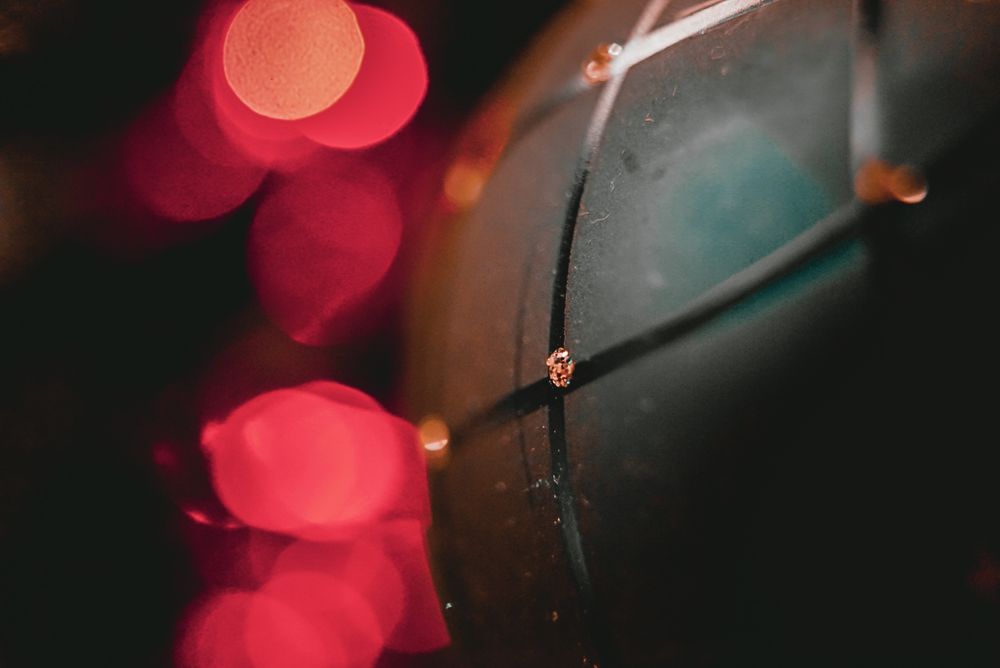 Close-up of a dark ornament with bokeh red lights in the background creating a festive holiday atmosphere.