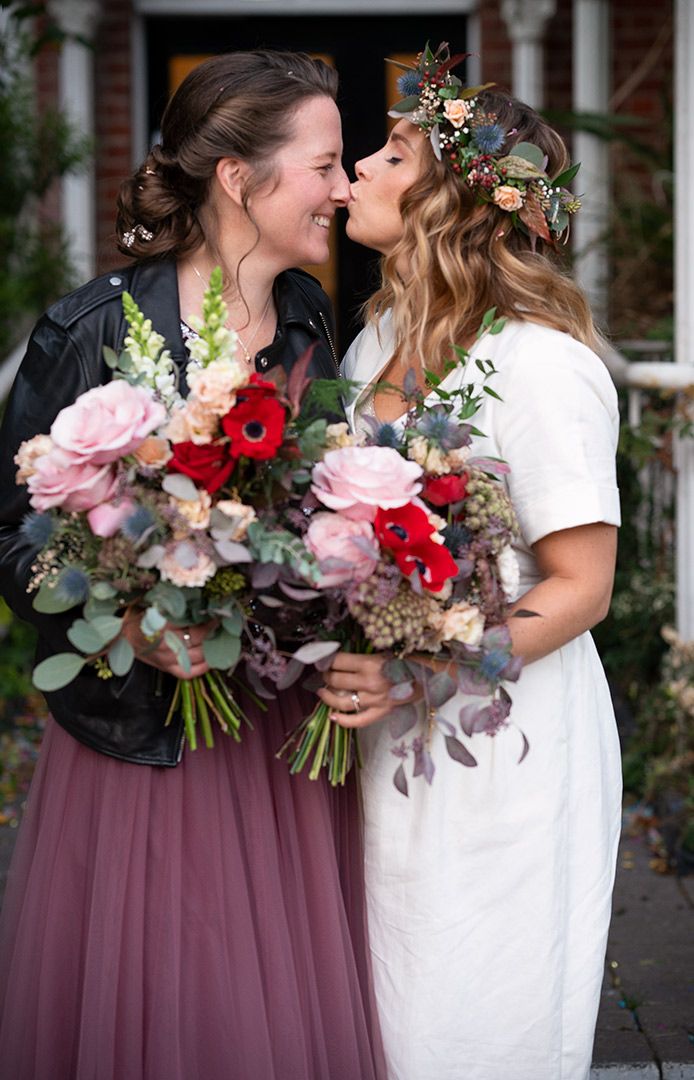 Wedding couple sharing intimate moment with beautiful floral bouquets and decorative headpiece.