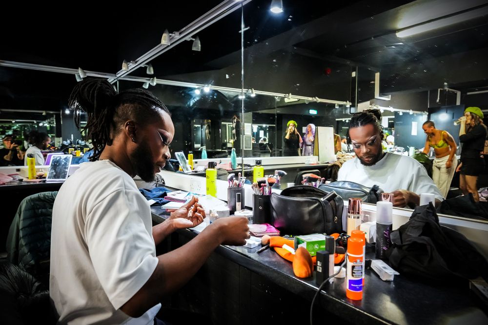 Busy dark barber shop interior with hair products and styling tools on counter at night.