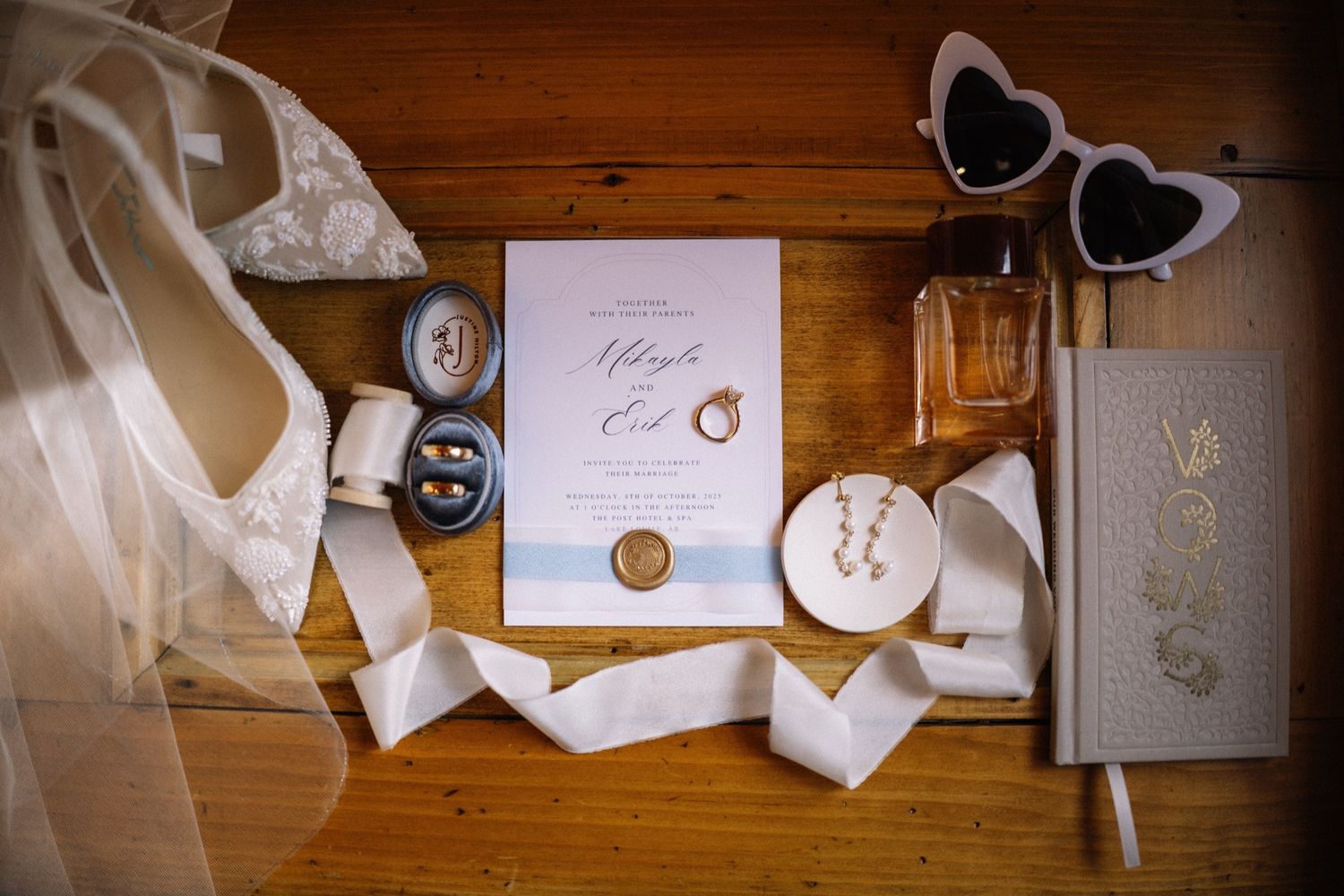 Post Hotel wedding flat lay with invitation, rings, ribbon and heart sunglasses