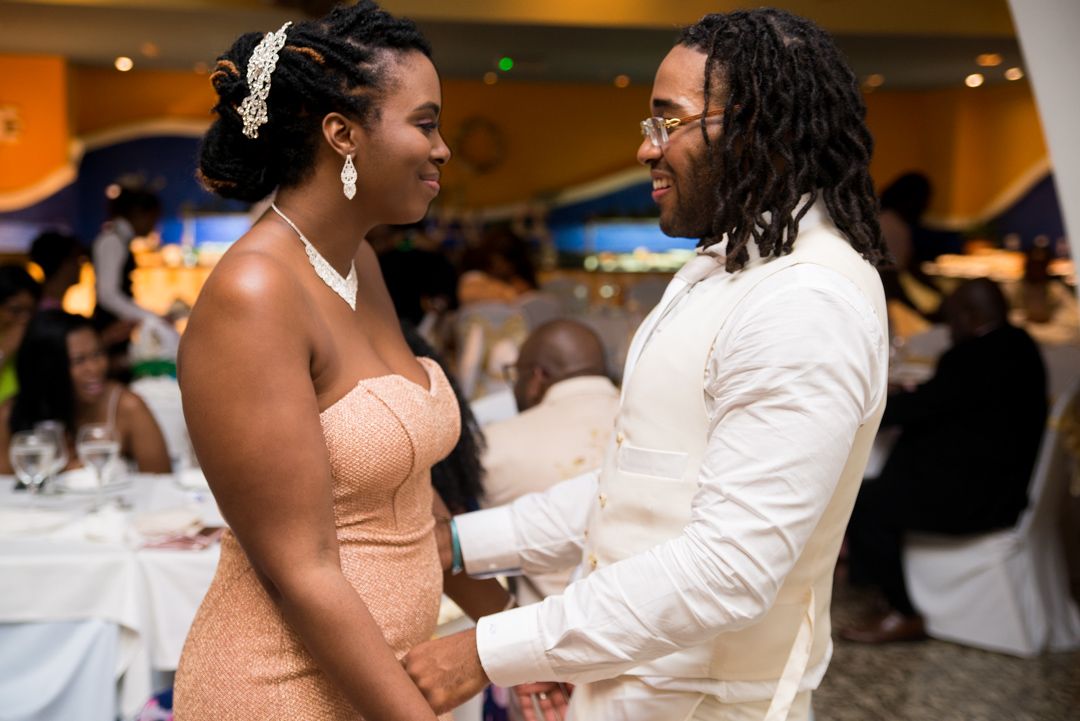 Couple sharing intimate moment at formal event with peach dress and white attire.