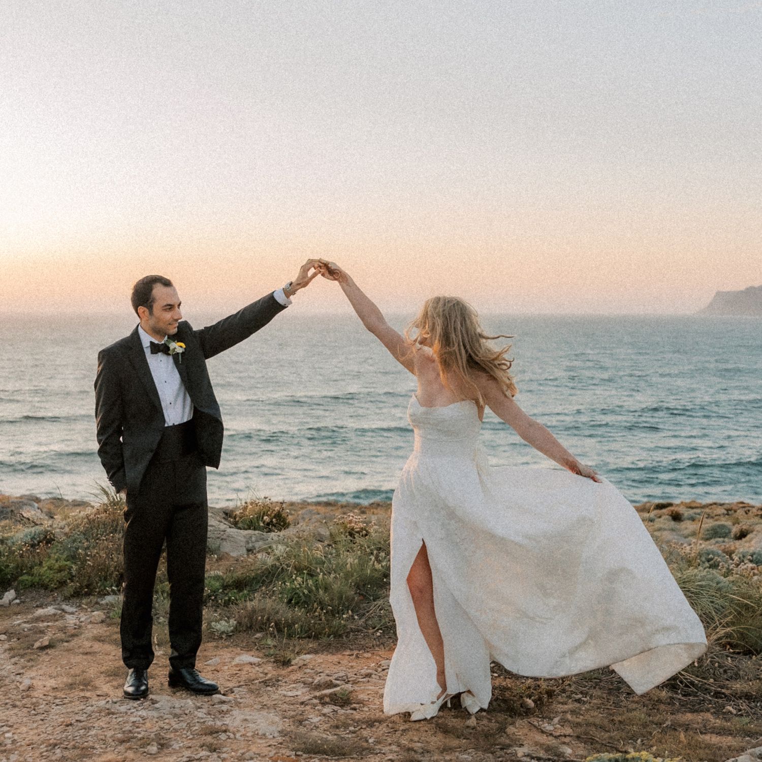 Bride twirling during sunset portraits overlooking the Atlantic coastline in Portugal.