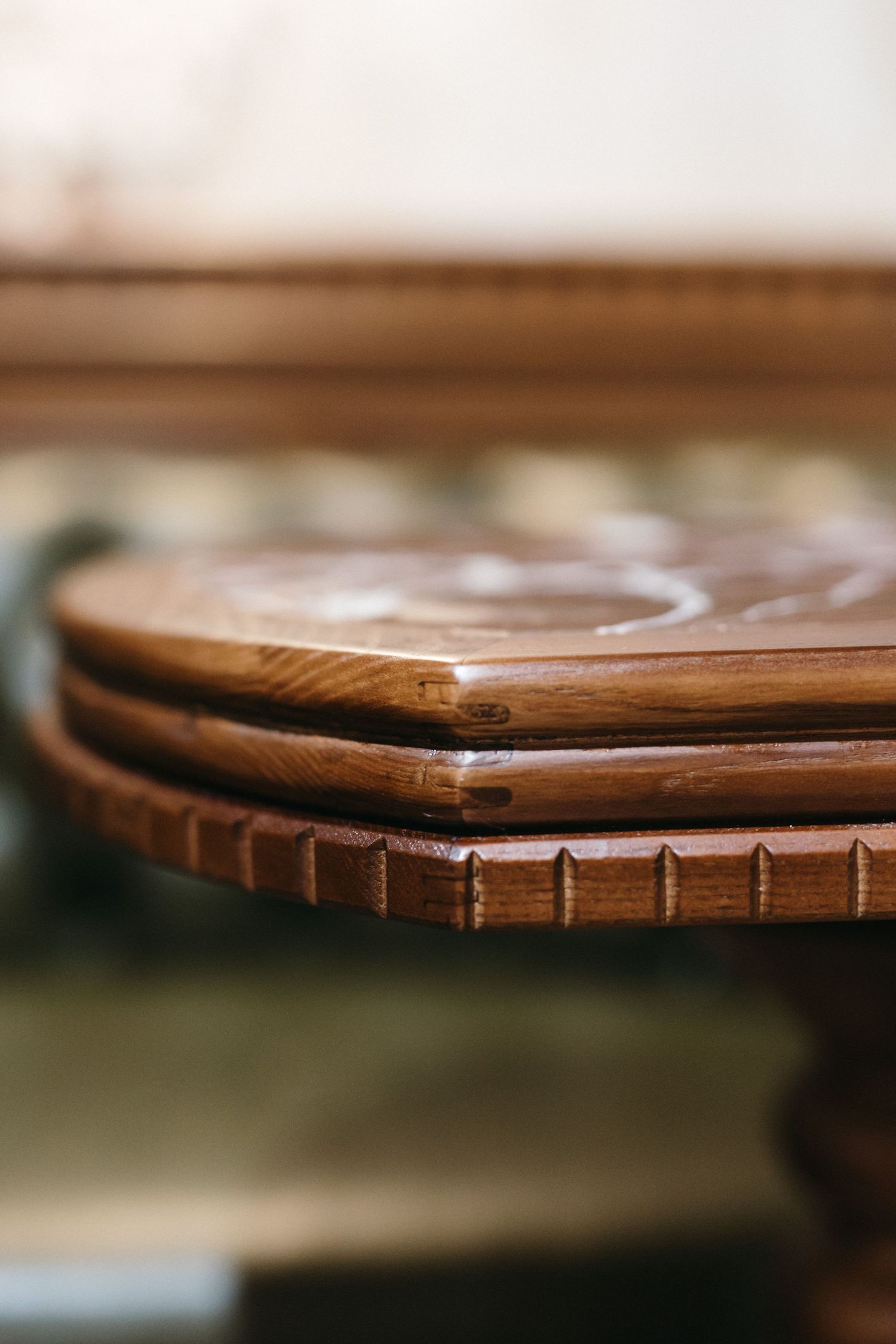 Close-up of a stacked ornate wooden cake stand with decorative carved edges and rich brown finish.