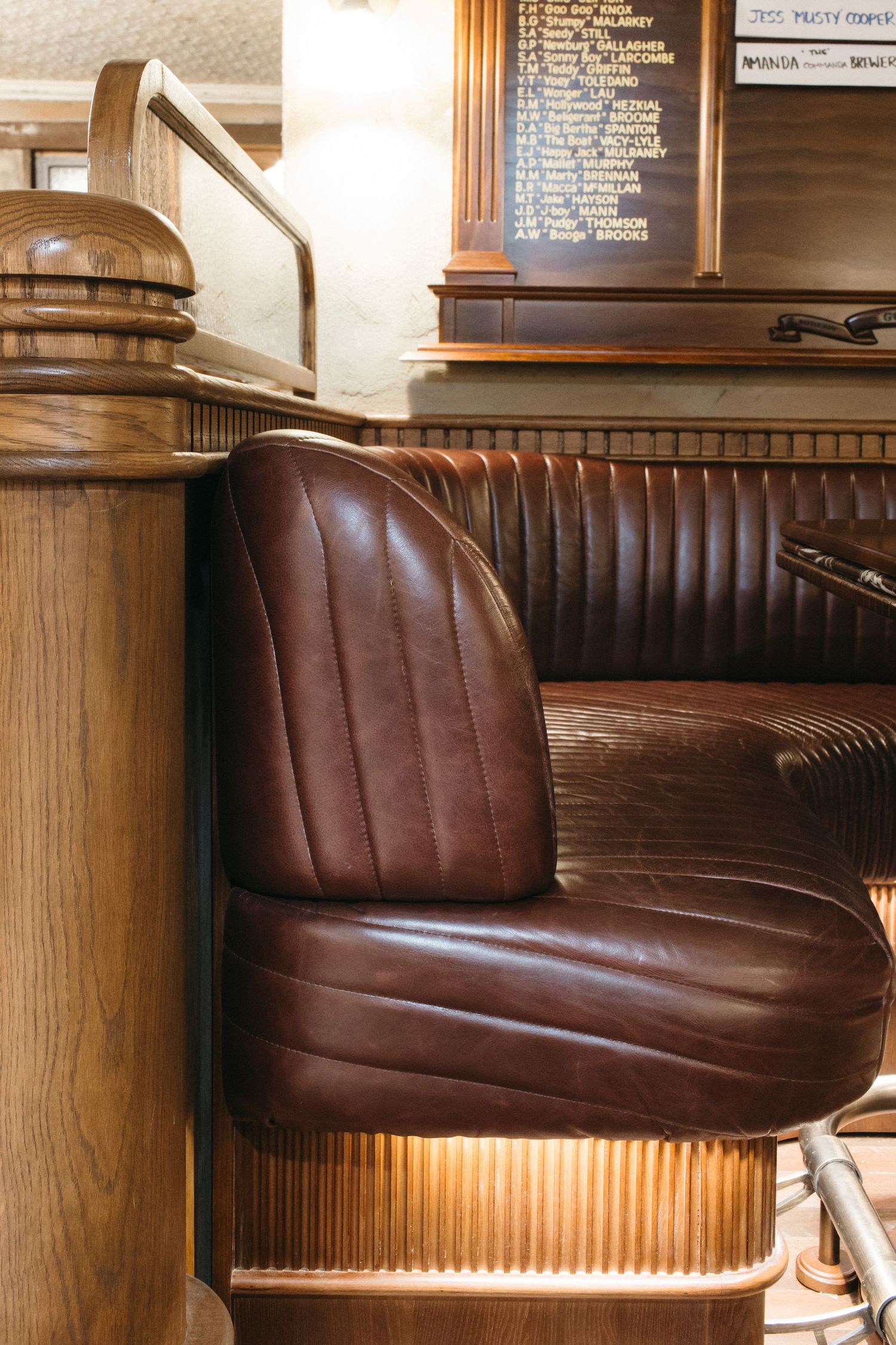 Vintage brown leather booth seat with ribbed detailing in a classic wooden bar interior.