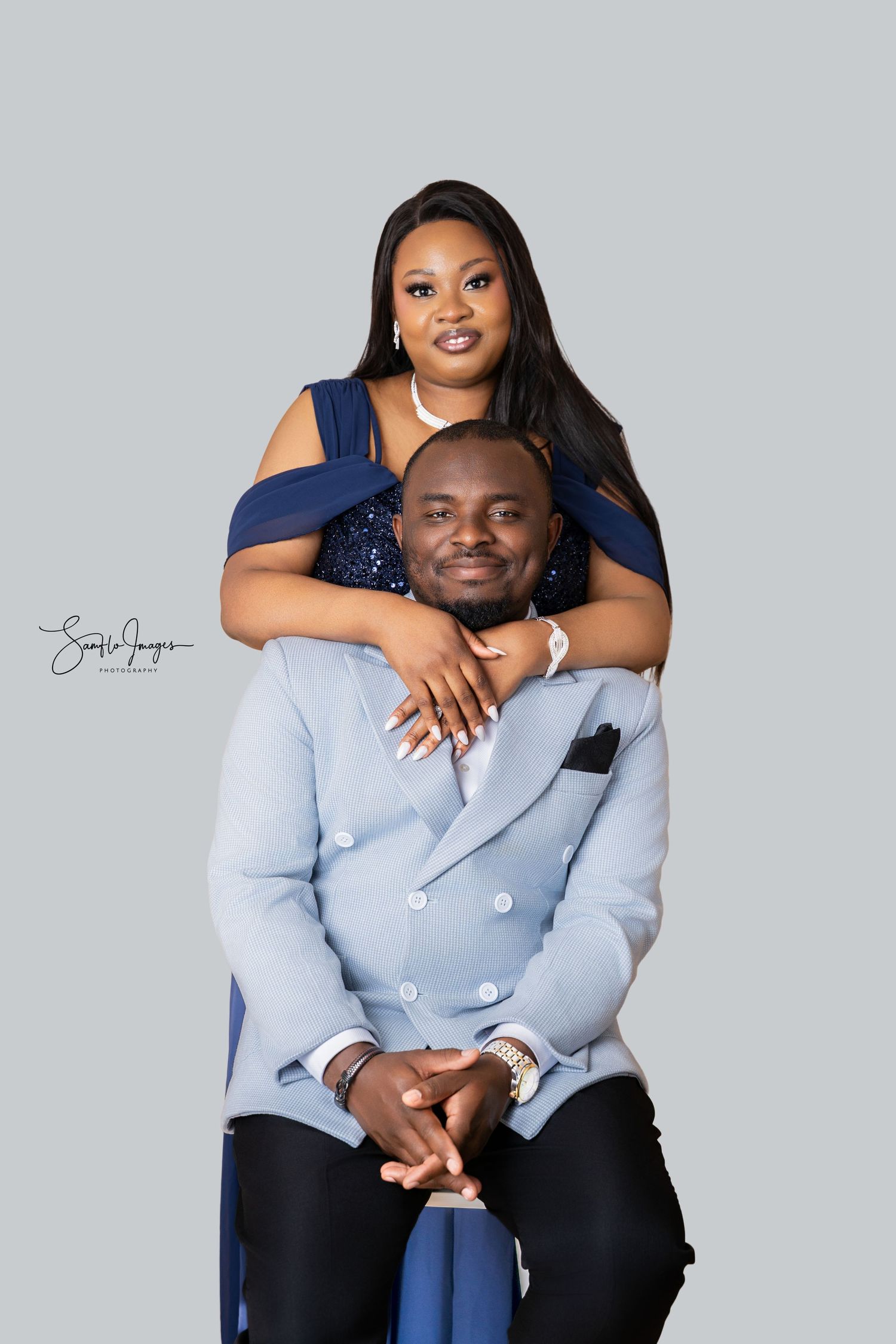 A couple poses elegantly in coordinating blue outfits for a professional studio portrait photo.