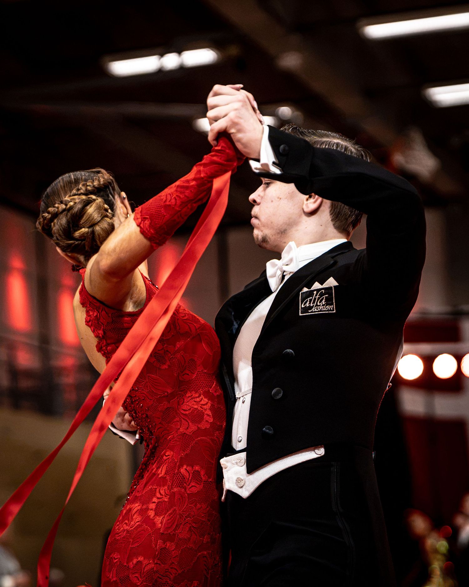 Elegant ballroom dancers perform in a blue rhinestone gown and black suit at a competitive dance event.