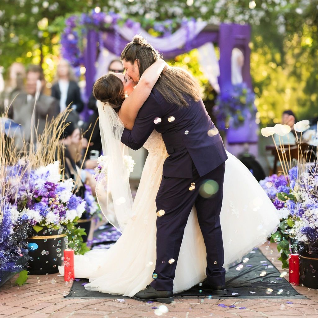 a wedding couple kisses in the aisle as bubbles fill the air