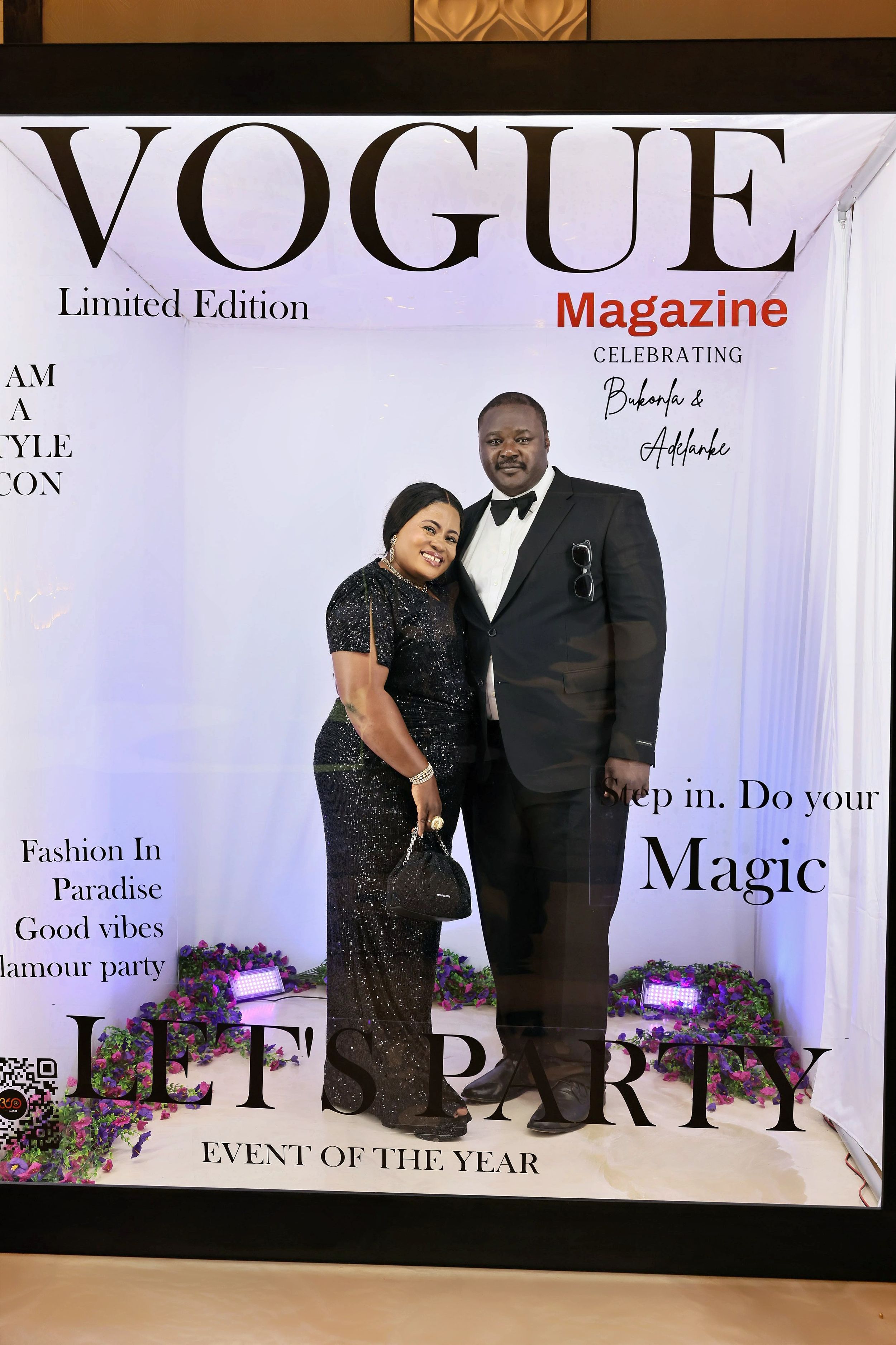 Elegant couple in formal black attire posing inside a Vogue Magazine Limited Edition party booth.