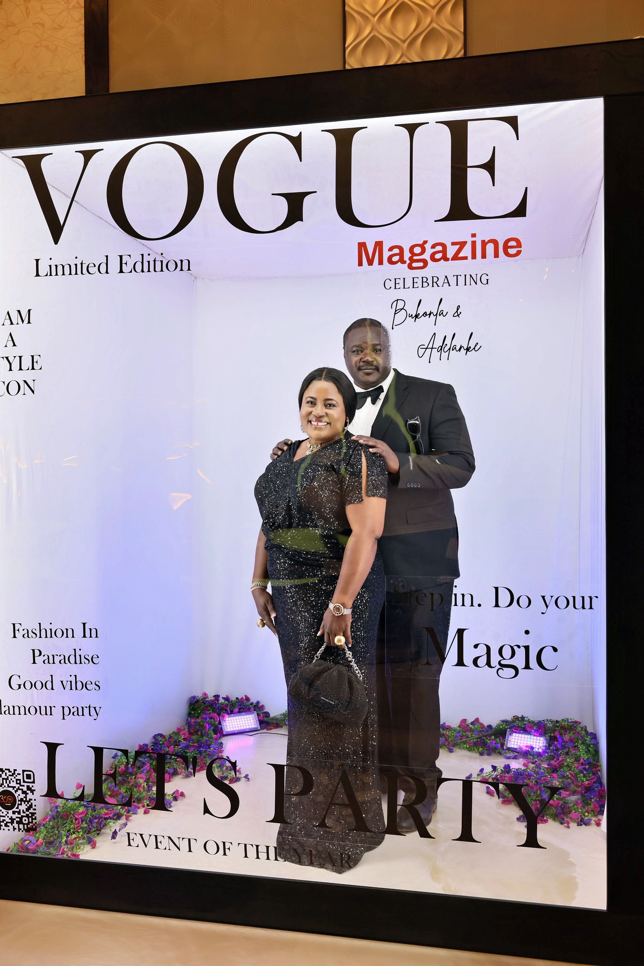 Stylish couple in black formal wear posing inside a Vogue Magazine Limited Edition party photo booth.