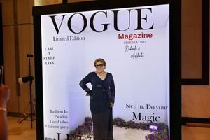 Woman in navy dress posing at Vogue Magazine Limited Edition Lets Party photo booth.