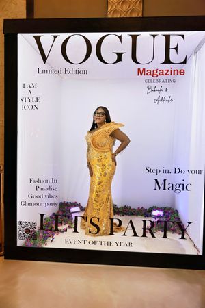 Woman in gold gown posing at Vogue Magazine Limited Edition Lets Party photo booth.