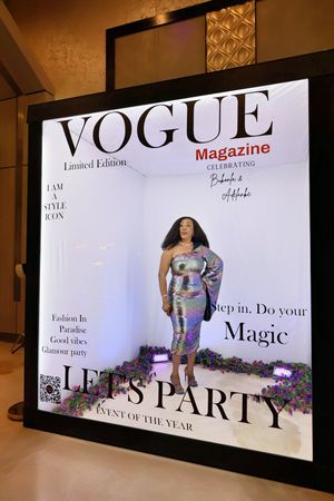 Woman in silver sequin dress posing in Vogue Magazine Limited Edition party photo booth at glamour event.
