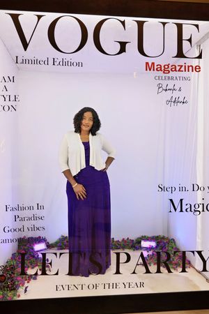 Woman in purple maxi dress posing at Vogue Magazine Limited Edition Lets Party booth.