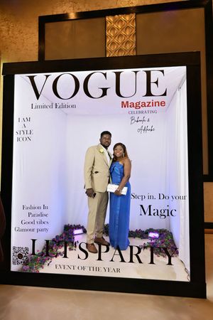 Couple posing in Vogue Magazine Limited Edition photo booth, man in tan suit and woman in blue dress.