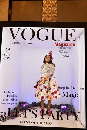Woman in floral dress posing in Vogue Magazine Limited Edition photo booth at glamorous party event.