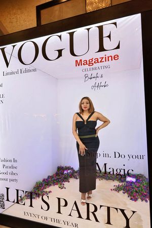 Woman in black dress posing in Vogue Magazine Limited Edition Let's Party event photo booth display.