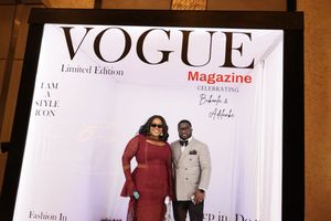 Couple in formal attire posing in Vogue Magazine Limited Edition photo booth at glamour party event.
