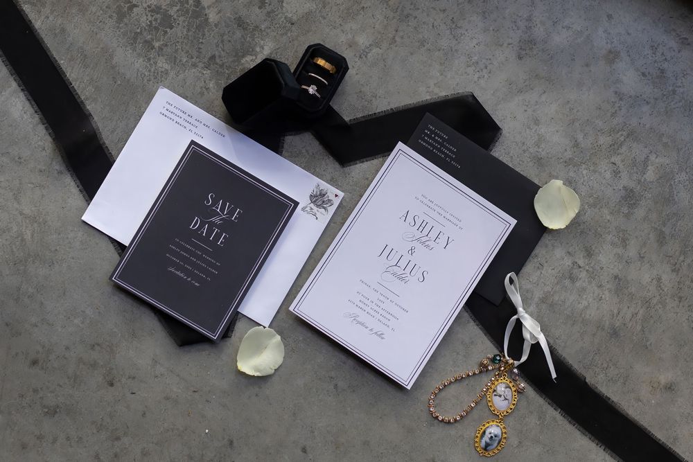 Elegant black and white wedding stationery suite with save the date card, invitation, ribbon, and decorative accessories.