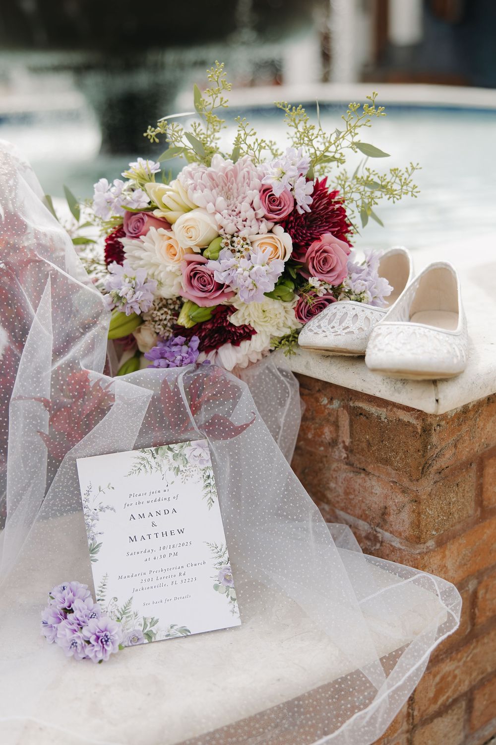 Elegant wedding flat lay with floral bouquet, bridal shoes, and invitation for Amanda and Matthew near a pool.
