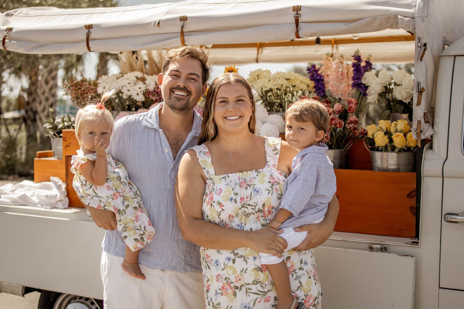 A toddler hugs a pregnant woman's belly beside a vintage VW van during a maternity photo session.