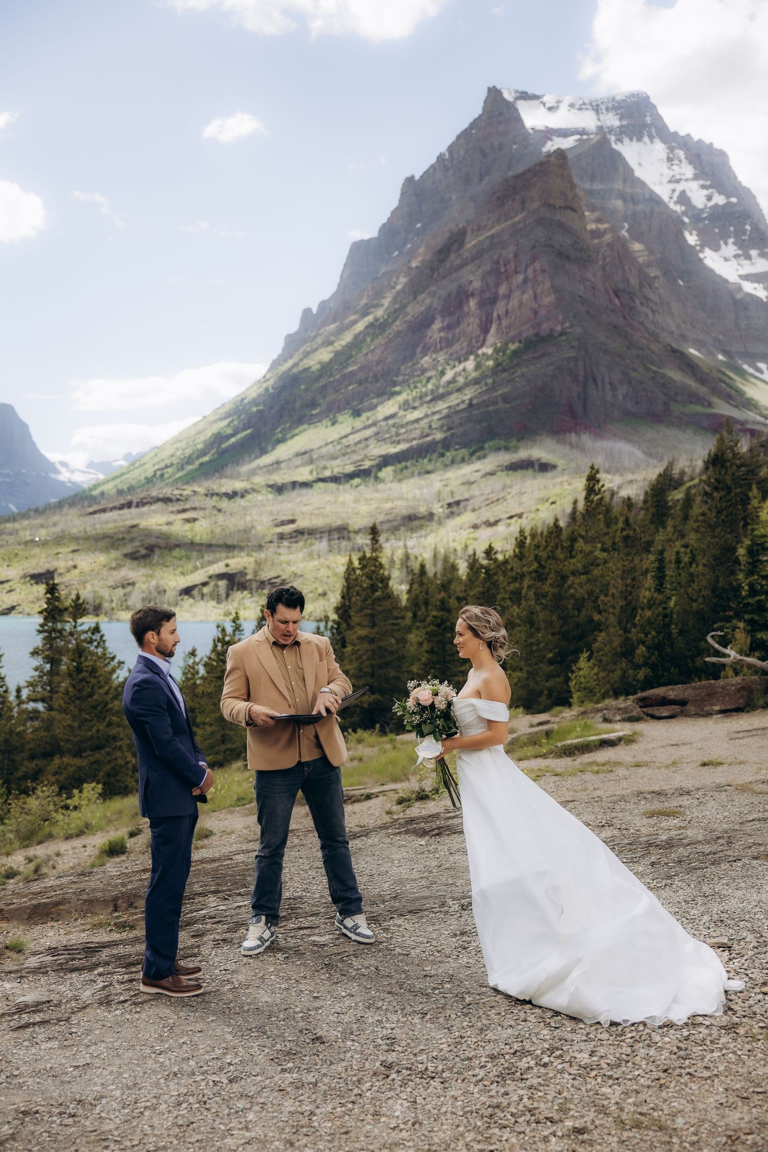 Outdoor elopement ceremony with bride and groom before officiant, stunning Rocky Mountain peaks and evergreen forest backdrop.