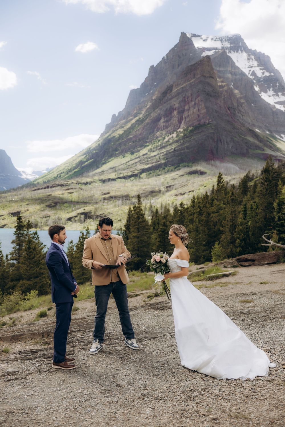 Outdoor elopement ceremony with bride and groom before officiant, stunning Rocky Mountain peaks and evergreen forest backdrop.