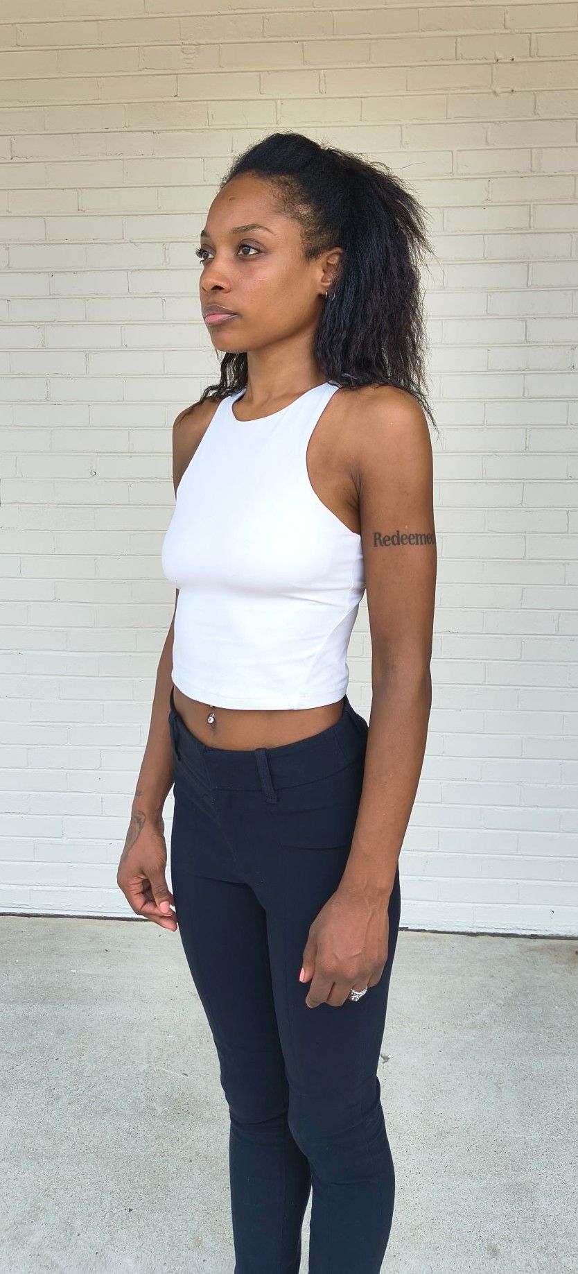 Three-quarter (left) digital of Genesis Dudley wearing a white tank top and black pants.