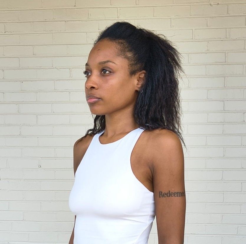 Three-quarter (left) portrait of Genesis Dudley with natural hair and no makeup.
