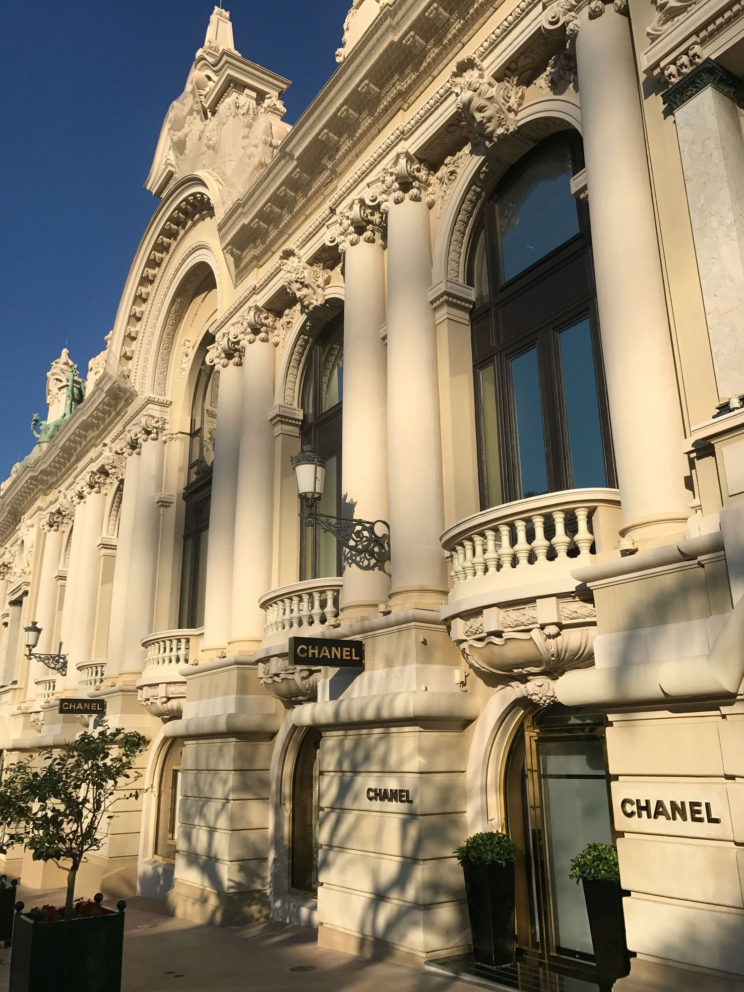 Chanel luxury boutique in ornate Beaux-Arts building with white stone facade, columns, and balconies under blue sky.