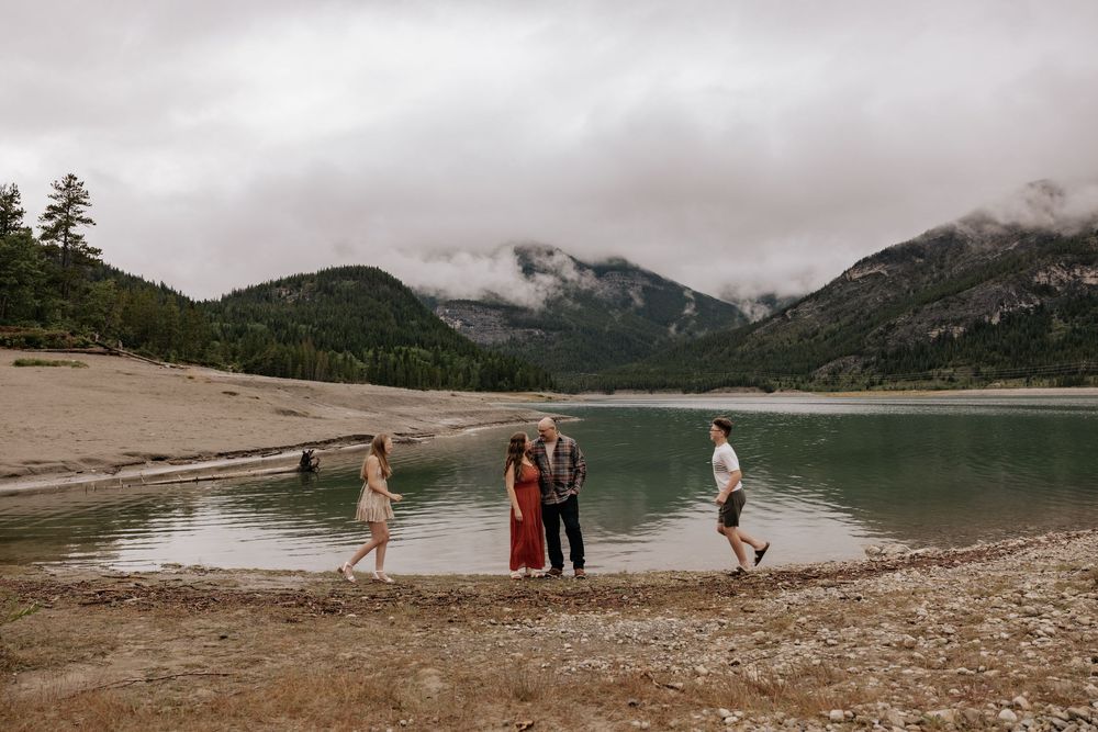 Family posing by a serene mountain lake in alberta Canada for family photoshoot