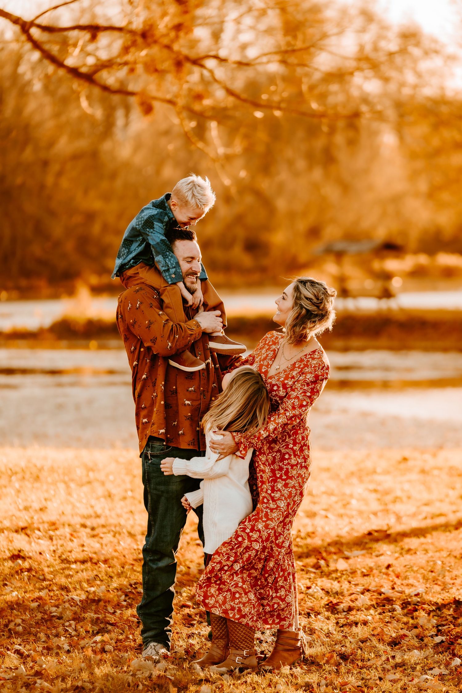 Joyful family in autumn park, father carrying son on shoulders, fall foliage background.