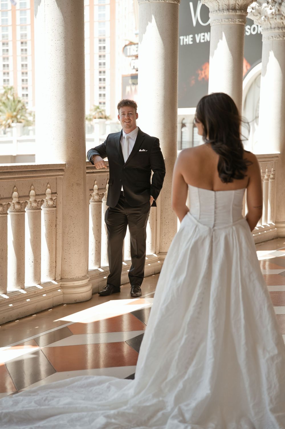 Bride in strapless white gown faces groom in black tuxedo at The Venetian Las Vegas wedding venue.