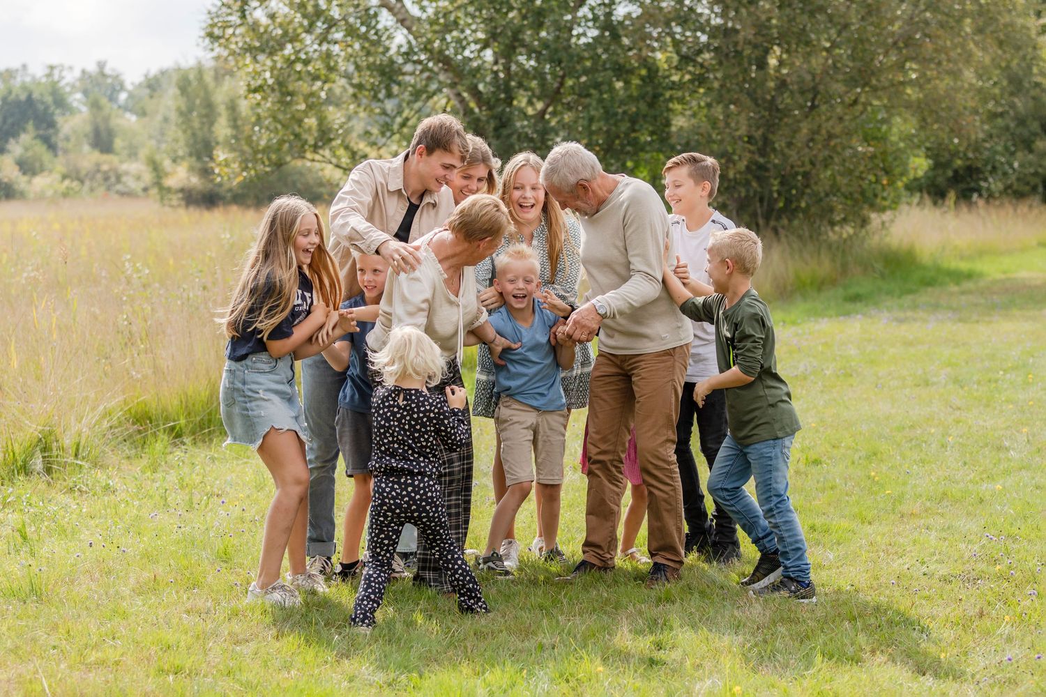 familiefoto waarbij opa en oma centraal staan en gekieteld worden door de kleinkinderen