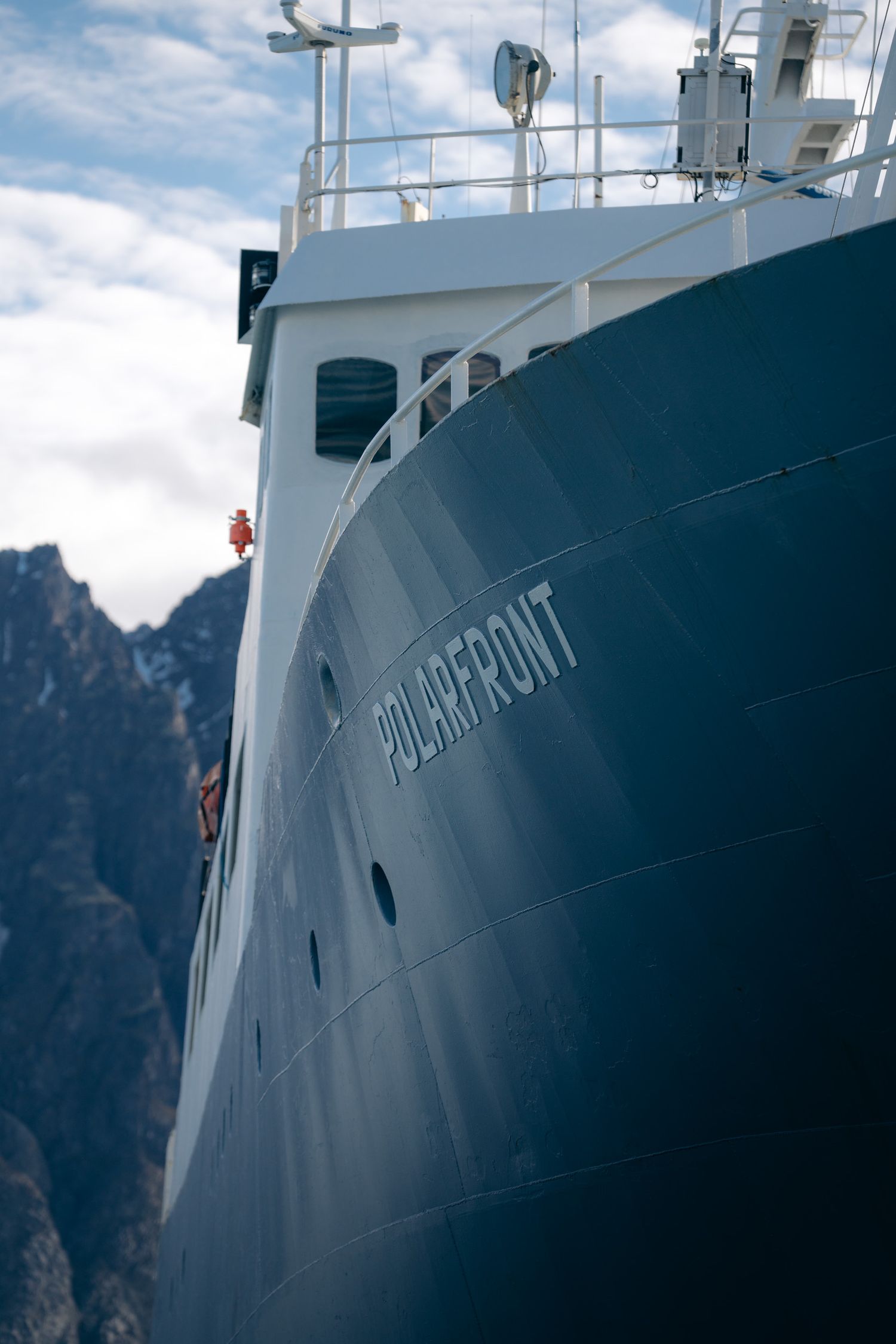 Étrave du Polarfront vue en contre-plongée devant une falaise sombre