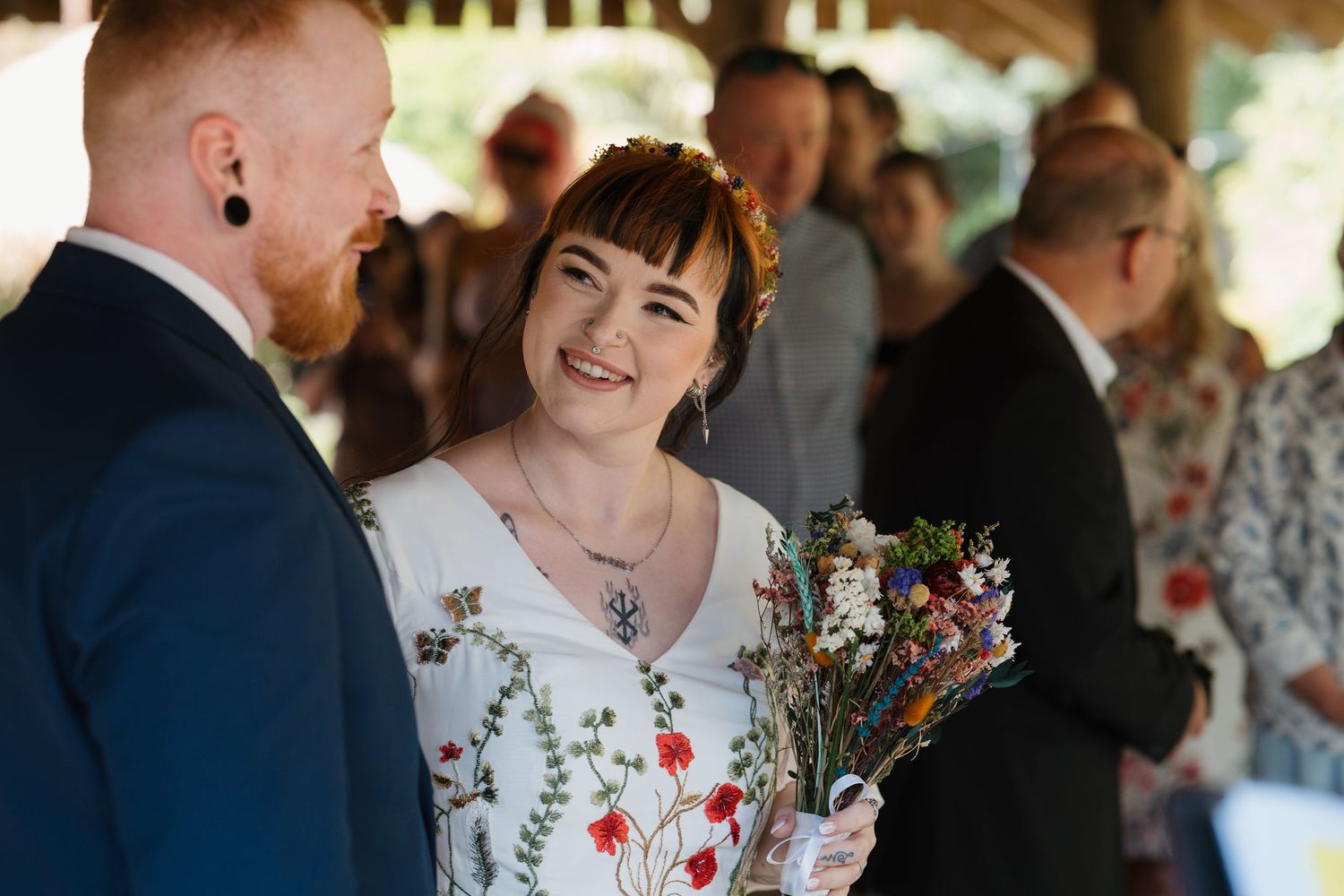 Bride and groom smiling in front of a lush green ivy wall with The View sign at their wedding venue.