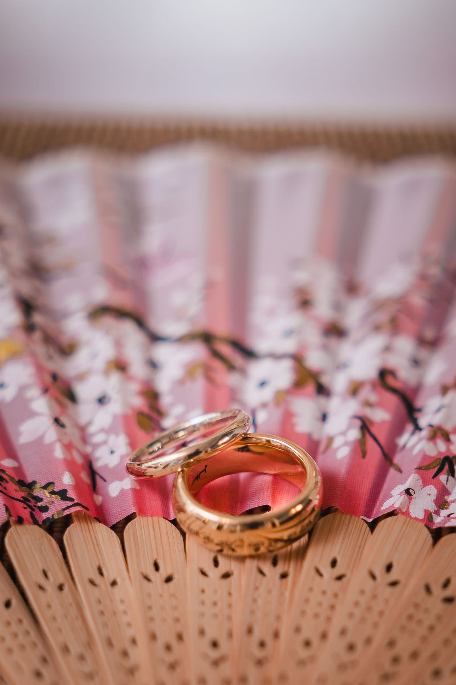 Close-up of the groom's wedding ring, engraved with Lord of the Rings script, resting on a patterned fan at Searles Castle.