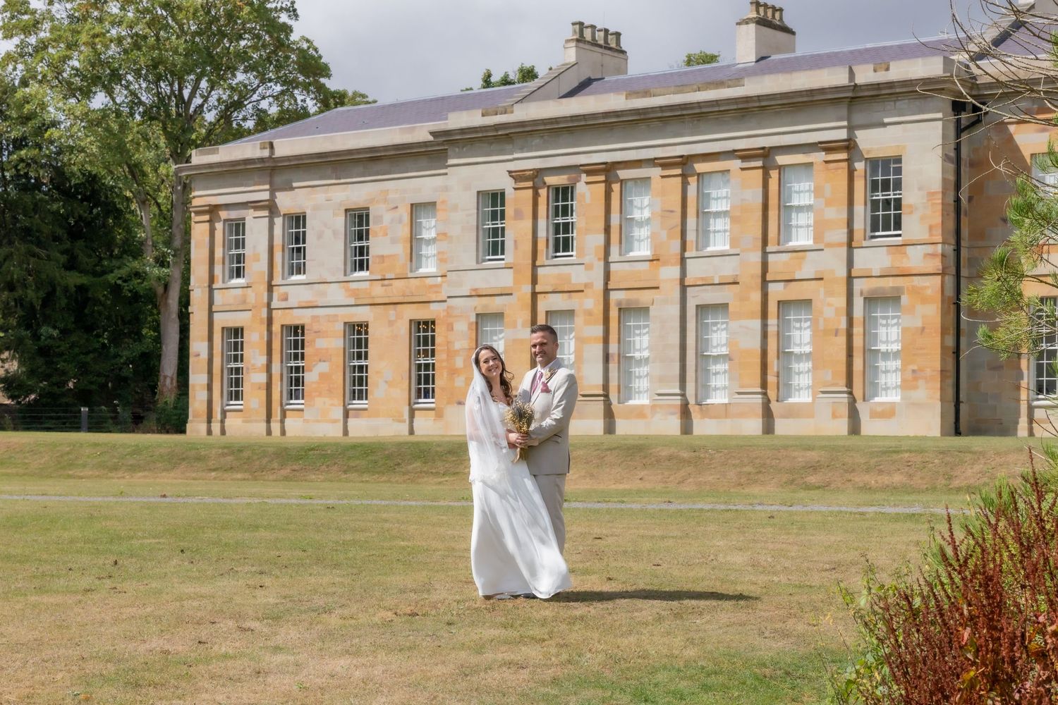 Bride and groom holding hands on lawn before The Story, Durham on sunny wedding day. Casual Captures UK