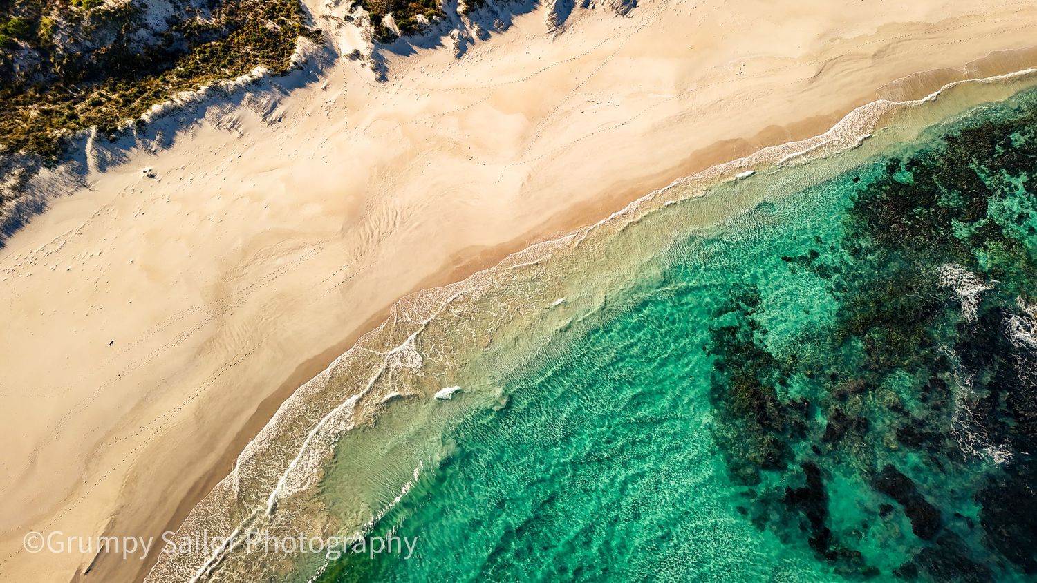 Aerial view of pristine sandy beach with turquoise ocean water.