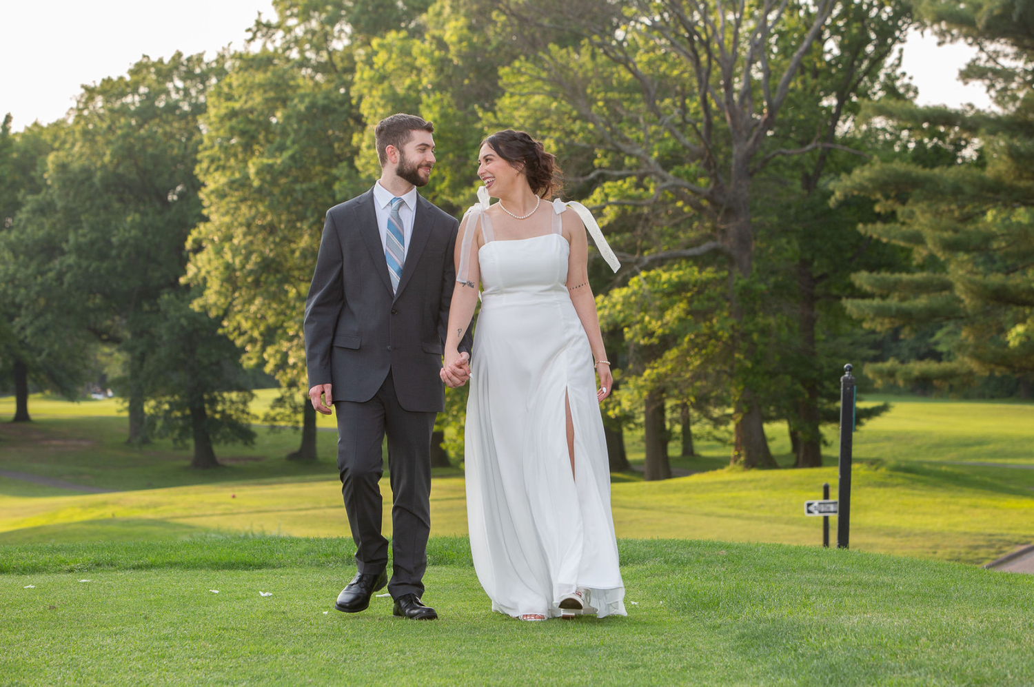 Bride in blue and white gown with groom in navy suit holding hands in elegant gold staircase venue.