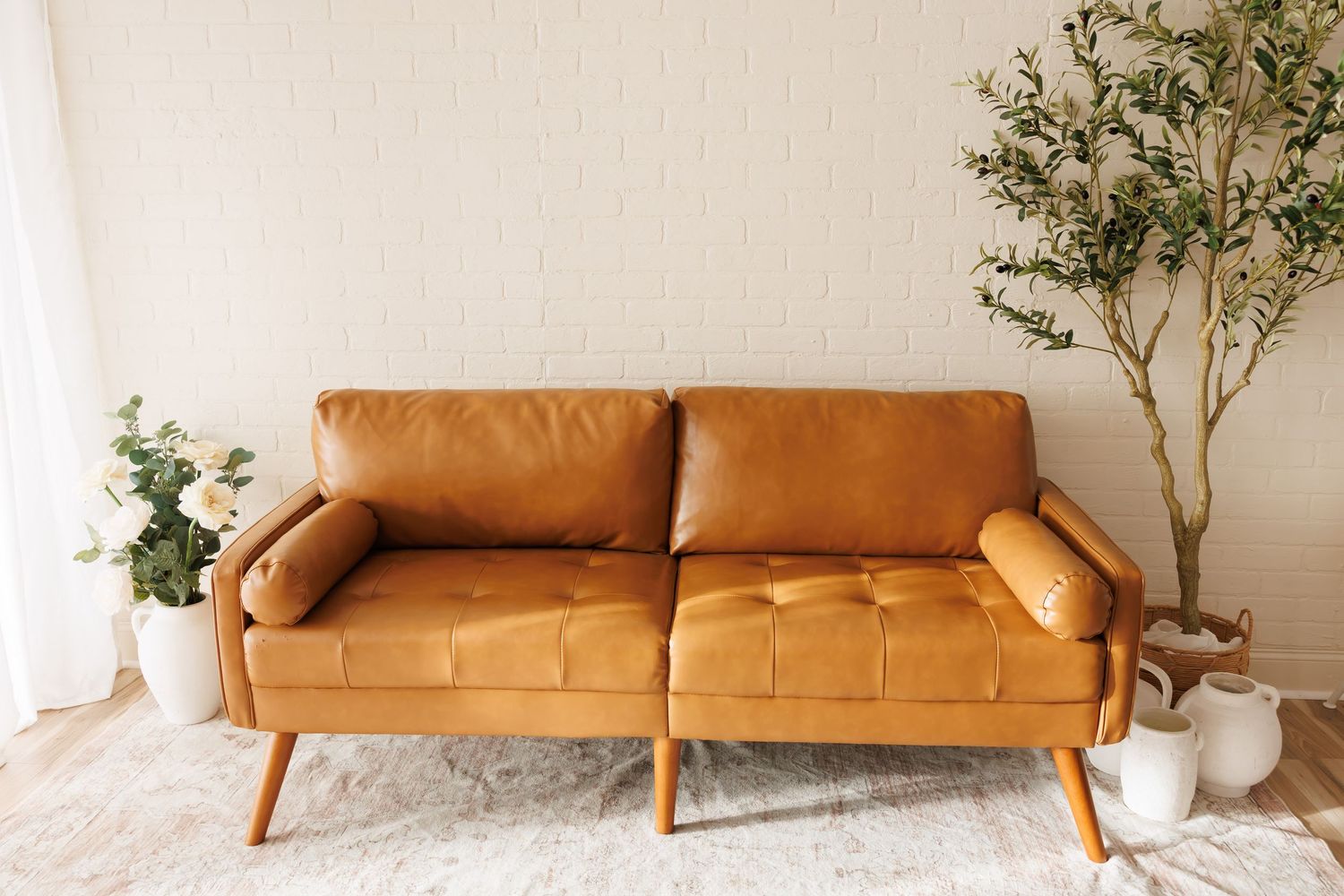 Bright studio space with orange sofa, white chairs, wood floors, and elegant decor perfect for events.