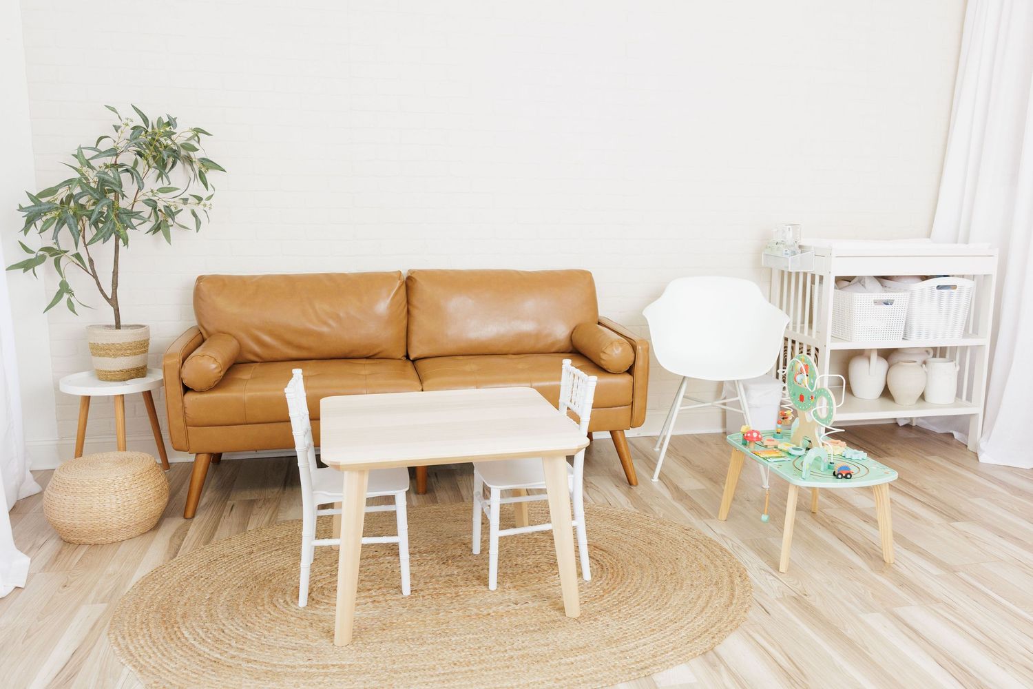 Bright studio space with orange sofa, white chairs, wood floors, and elegant decor perfect for events.