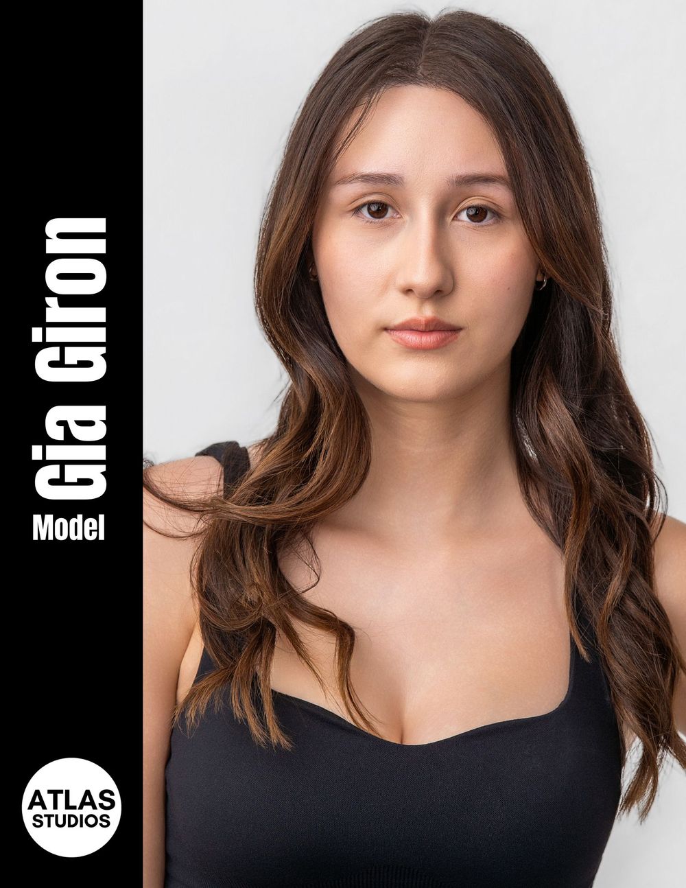 Professional headshot of model Gia Giron with long brown wavy hair wearing a black top for Atlas Studios.
