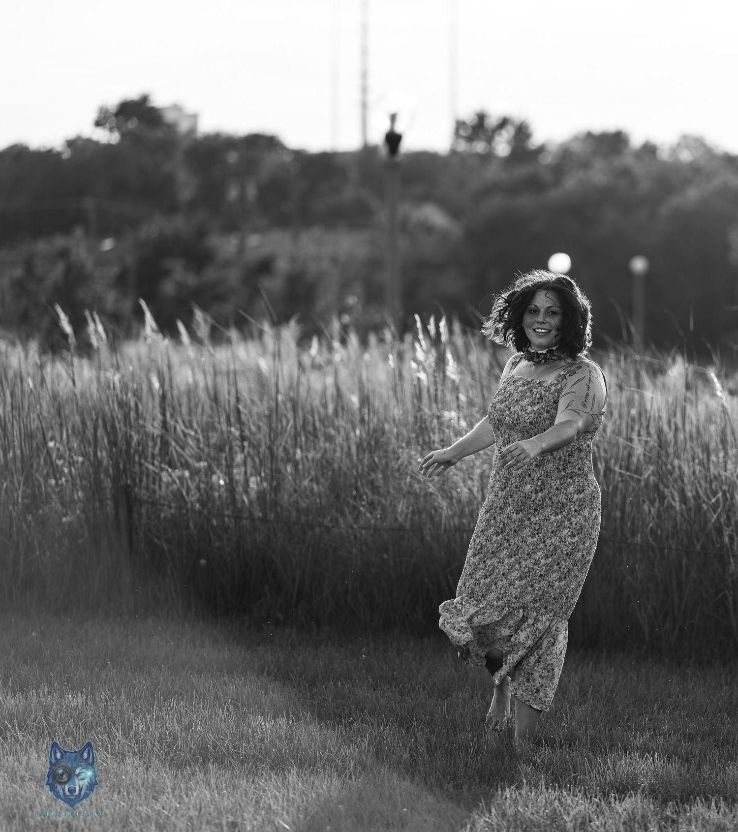 Black and white photo of woman in floral dress dancing in field at dusk. Chi.Shooters meet gabbsbosh