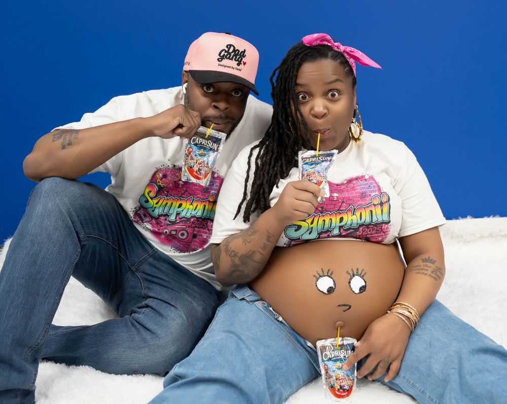 Couple in Simpsons shirts posing with painted baby bump during fun maternity photoshoot.