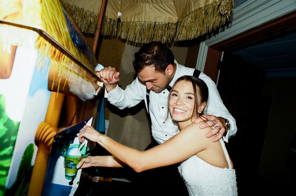 Bride and groom cutting wedding cake together, smiling joyfully at their reception celebration.