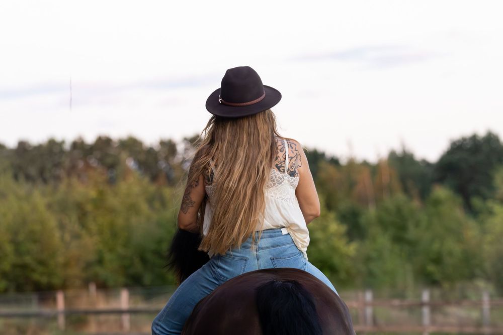 Meisje met hoed zit op zwart paard